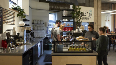 Baristas behind a counter serving two customers